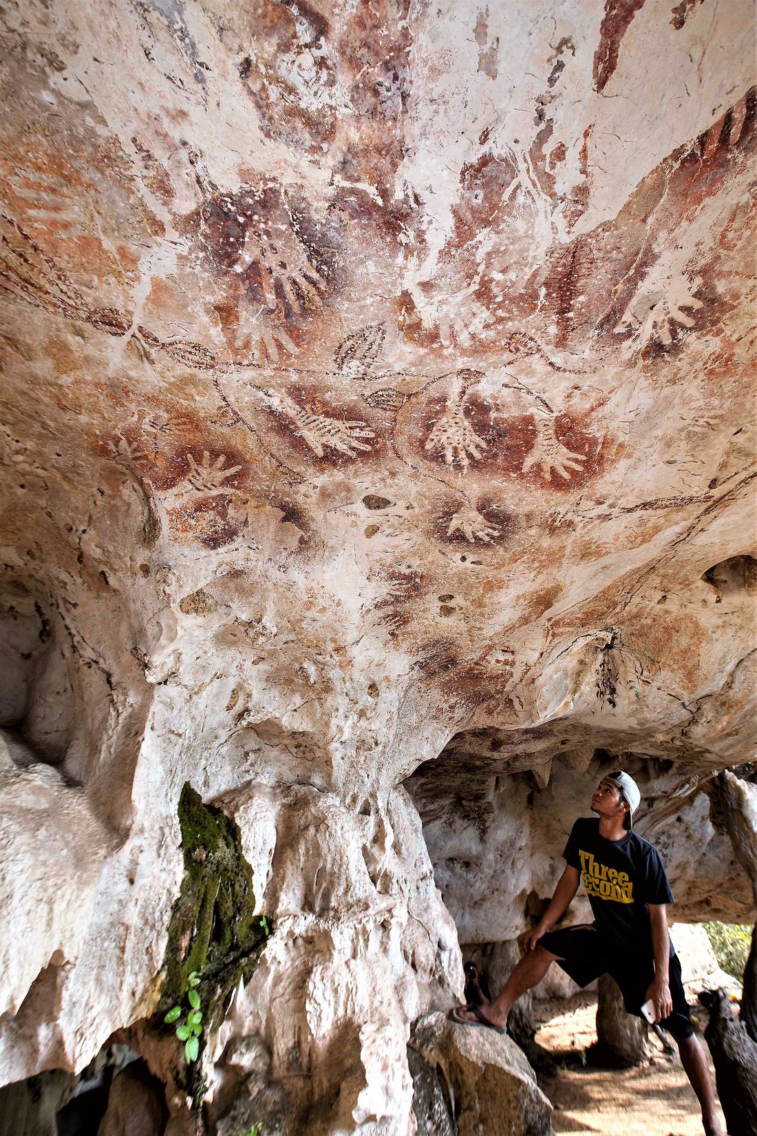 Ancient red hand stencils on a cave ceiling in the Sangkulirang–Mangkalihat karst, Borneo